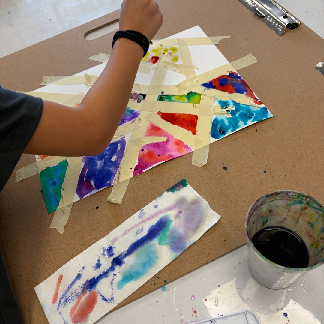 Student painting a colorful watercolor tape resist artwork